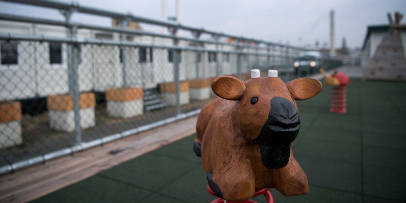 Eine Kinderwippe steht am 01.12.2017 auf einem Kinderspielplatz vor einigen der fast 900 Container auf dem Gelände der Gemeinschaftsunterkünfte für Geflüchtete auf dem Tempelhofer Feld in Berlin. In das Containerdorf, den sogenannten Tempohomes, ziehen An