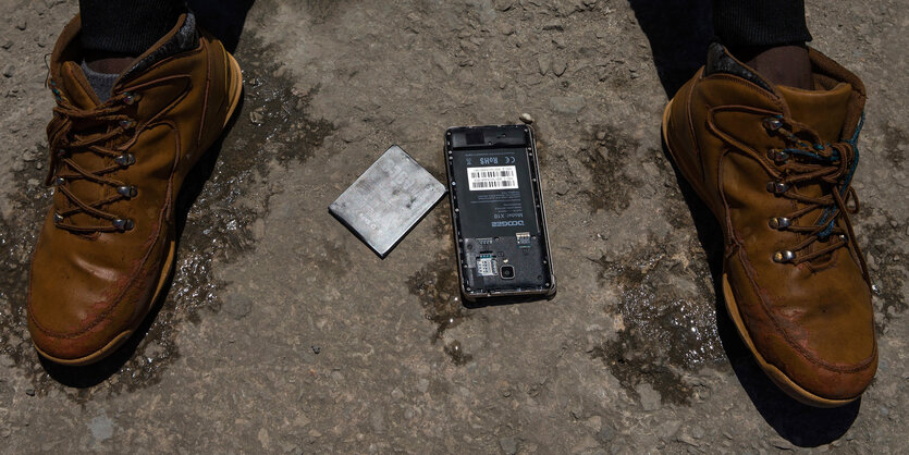 Das nasse Mobiltelefon eines Flüchtlings, der aus der Straße von Gibraltar, gerettet wurde, liegt zum Trocknen in der Sonne