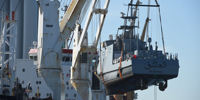 Ein kleines Schiff hängt am Kran eines größeren Schiffes