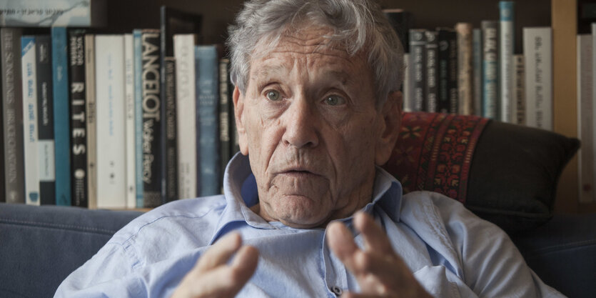 Amos Oz vor einem Regal mit Büchern