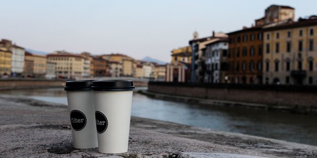 Szene am Arno in Pisa: Zwei Kaffeebecher vor dem Fluss