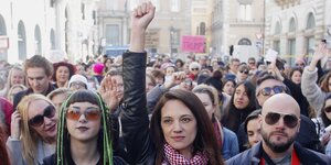 Asia Argento steht zwischen DemonstrantInnen und reckt die Faust nach oben