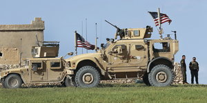 zwei beigefarbene Armee-Fahrzeuge mit US-Flagge