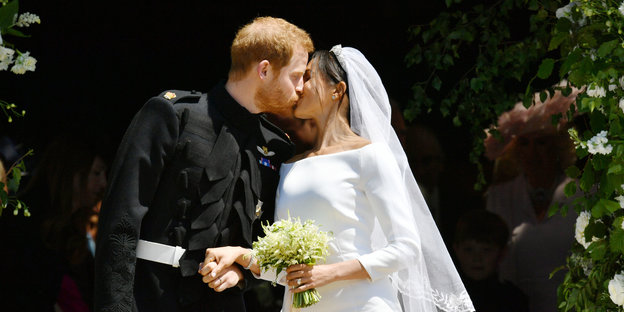 Mann in Uniform und Frau in weißem Kleid küssen sich