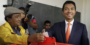 Junger Mann mit Anzug und Krawatte an einer Wahlurne