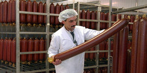 Ein Mitarbeiter des Bremer Wurstherstellers Könecke hält im Werk im polnischen Slubice eine große Salami in seinen Händen.