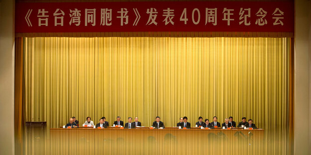 Ein Panel mit 17 Männern und einer Frau in einem hohen Saal