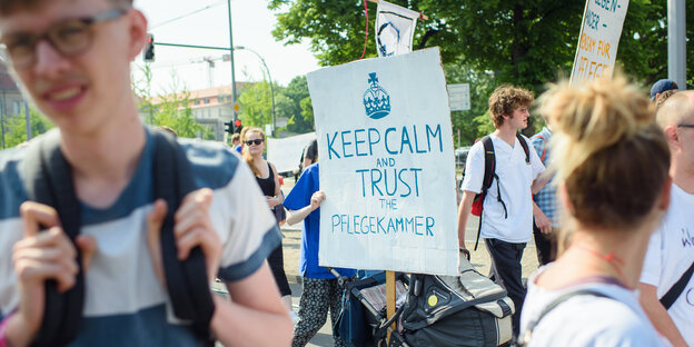 Eine Teilnehmerin hält auf einer Demonstration für bessere Arbeitsbedingungen in der Pflegebranche ein Schild mit der Aufschrift "Keep Calm and Trust the Pflegekammer".