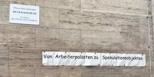 An einer Wand in der Karl-Marx-Allee klebt ein Spruch: Von Arbeiterpalästen zu Spekulationsobjekten