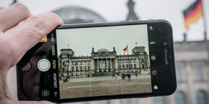 Ein Handybildschirm zeigt das Foto des Bundestags