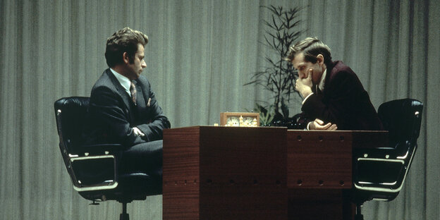 Boris Spasski und Bobby Fischer sitzen sich gegenüber, in der Mitte steht ein Tisch mit einem Schachbrett