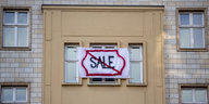 Aus einem Haus hängt ein Transparent mit durchgestrichenem "Sale"-Aufdruck
