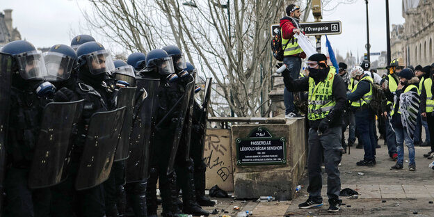 Polizisten stehen während eines Protests Demonstrierenden mit gelben Westen gegenüber