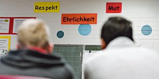 Über einer Tafel hängen drei Zettel mit den Worten "Respekt", "Ehrlichkeit" und "Mut".