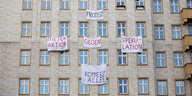 An einer Gebäudefassade hängen Transparente, u.a. „Protest“ und „Mieteraktion gegen Spekulation“