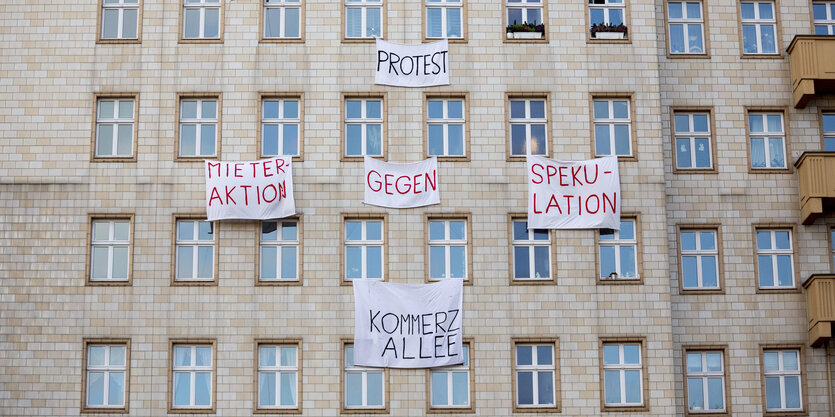 An einer Gebäudefassade hängen Transparente, u.a. „Protest“ und „Mieteraktion gegen Spekulation“