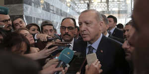 Erdogan steht inmitten von Journalisten und spricht in Mikrofone