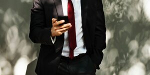 Ein Mann in Anzug guckt auf sein Smartphone