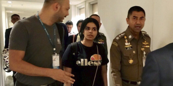 Rahaf Mohammed al-Kunun steht zwischen zwei Männern