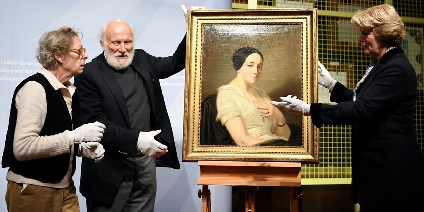 Kulturstaatsministerin Monika Grütters übergibt den Erben Maria de las Mercedes Estrada und Wolfgang Kleinertz, das Bild "Portrait de jeune femme assise" des Künstlers Thomas Couture