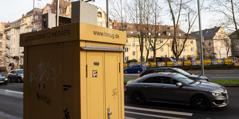 Autos fahren an einer Luftmessstation des Luftmessnetz Hessen am Straßenrand der Schiersteiner-Straße vorbei.