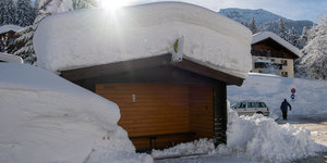 Bushaltestelle in Schneelandschaft: auf dem Dach einer Holzhütte liegt viel Schnee