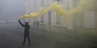 Demonstrant mit Pyro, das gelben Rauch abgibt