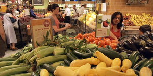 Eine handvoll Menschen sind in der Gemüseabteilung eines Supermarktes zu sehen