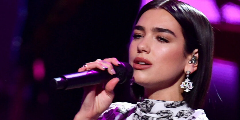 Die Sängerin Dua Lipa singt in ein Mikrofon