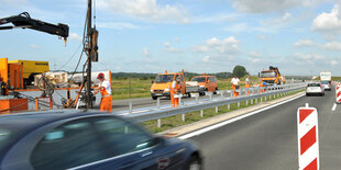 Bauarbeiter stehen auf der A26 bei Horneburg.