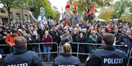 In Leipzig steht eine Menschenmenge hinter einem Absperrgitter vor dem Polizisten stehen