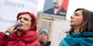 Linken-Parteichefin Katja Kipping (l.) und Grünen-Fraktionschefin Katrin Göring-Eckardt stehen nebeneinander auf einer Kundgebung im Jahr 2015, zwischen ihnen hält jemand ein Schild mit dem Gesicht des US-Whistleblowers Edward Snowden hoch.
