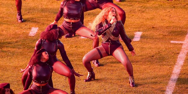 Beyoncé mit Tänzerinnen auf einem Football-Feld