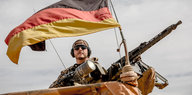 Ein Soldat auf einem Stützpunkt mit Deutschlandflagge und Maschinengewehr