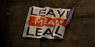 Auf einem zerknitterten Schild steht „Leave means leave“. Das Schild liegt auf dem Boden