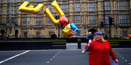 Frau im roten Pulli hält goldene Luftballons in Form der Buchstaben E und U in die Höhe