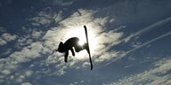 ein Skifahrer schlägt einen Salto in der Luft im Gegenlicht
