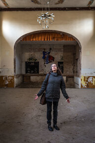 Eine Frau steht in einem großen Saal und blickt an die Decke Eine Frau steht in einem großen Saal und blickt an die Decke