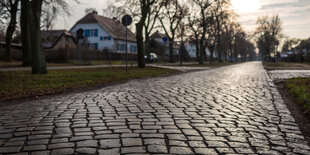 eine Pflastersteinstraße führt auf ein Dorf zu