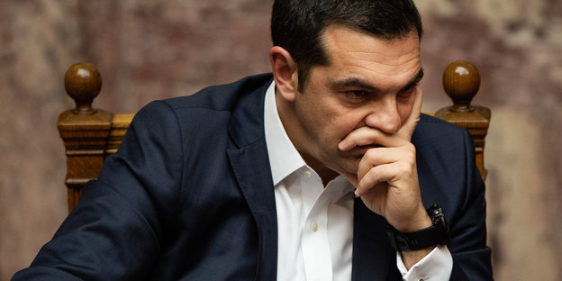 Ein Mann stützt seinen Kopf auf seine Hand. Es ist Alexis Tsipras