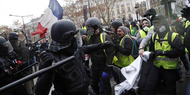 Ein Polizist setzt einen Schlagstock gegen Demonstranten der Gelbwesten ein