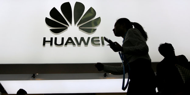 Silhouetten vor einem Huawei-Schild