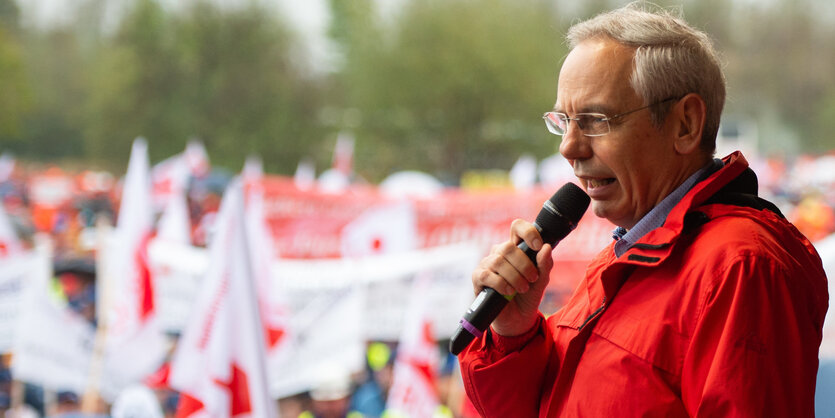 Mann spricht mit Mikro vor Demonstranten