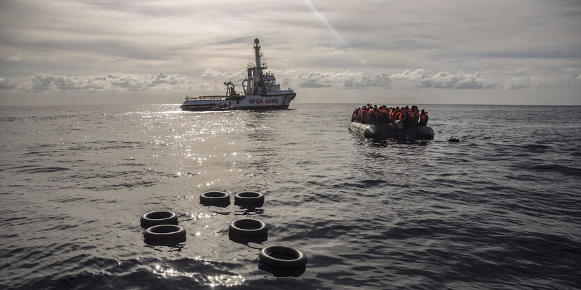 Ein Boot mit Menschen darauf, im Hintergrund ein Schiff