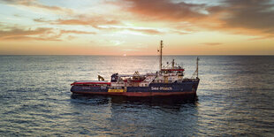 Ein Schiff allein auf weiter See, vor untergehender Sonne