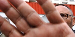 AfD-Mann Frank Magnitz hält seine Hand vor die Kamera