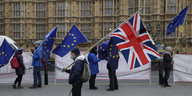 Menschen mit britischen und EU-Flaggen stehen statisch nebeneinander auf einem Platz
