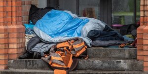 Ein Obdachloser liegt unter einer Decke in einem Eingang einer Kirche in Kreuzberg