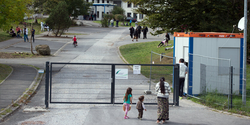 Eine Frau und zwei Kinder vor dem Tor der Flüchtlingsunterkunft Burbach