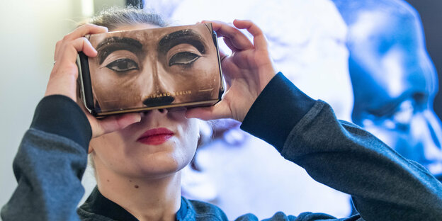 Eine Frau hält sich eine VR-Brille vor das Gesicht